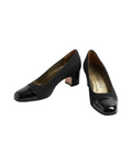 Pair of black patent leather YSL vintage shoes on a white background