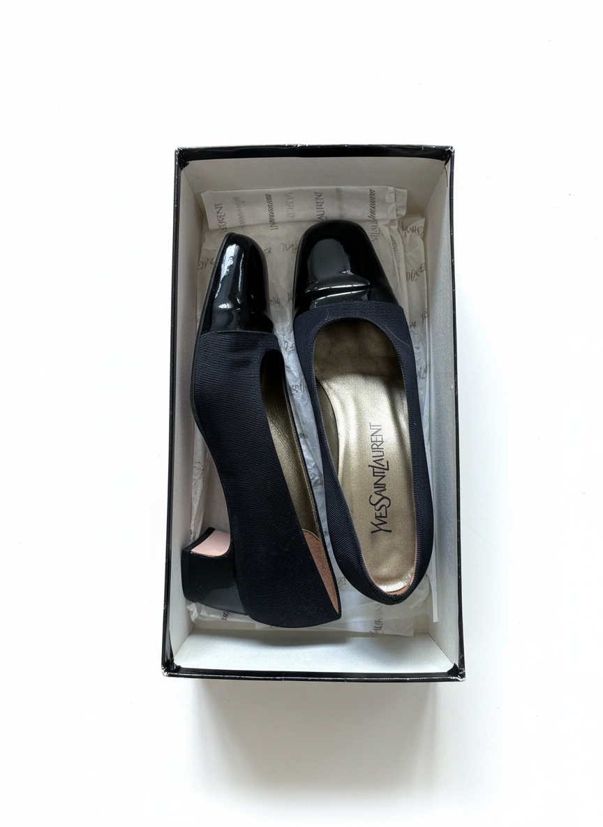 Black vintage shoes in a Yves Saint Laurent box on a white background